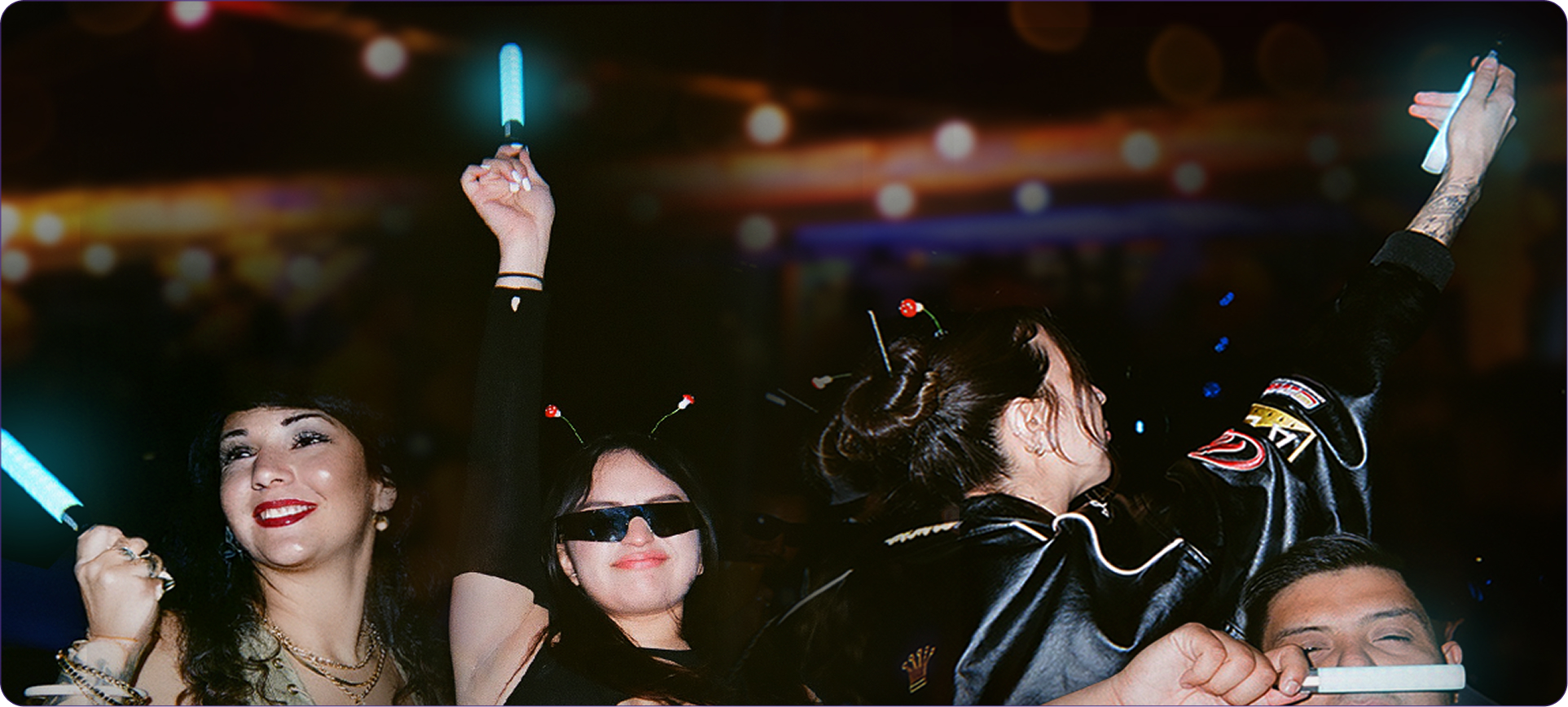 A crowd at night with Litsabers raised and lit above the dance floor