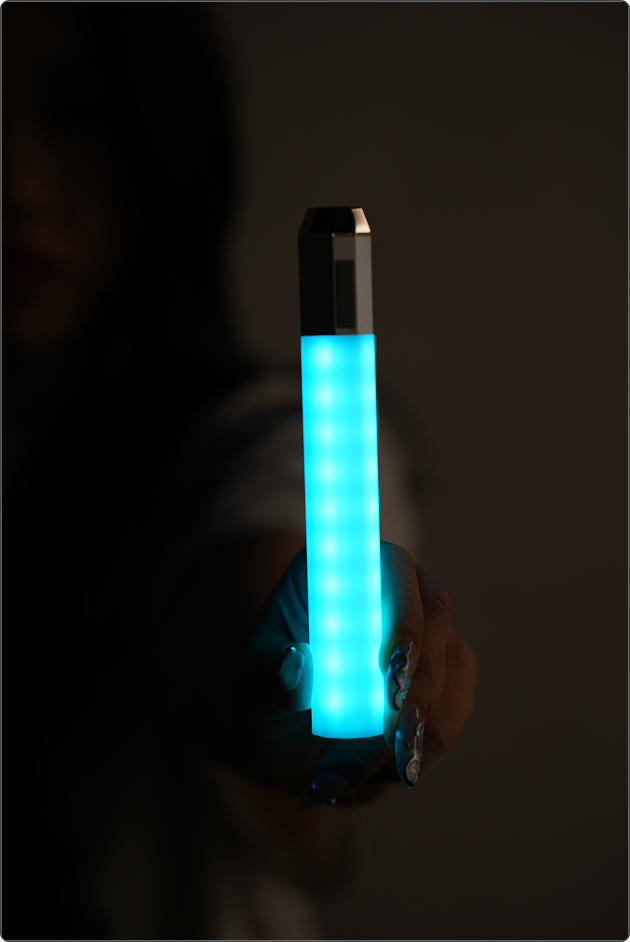A Litsaber glowing cyan, held out toward the camera in a dark room